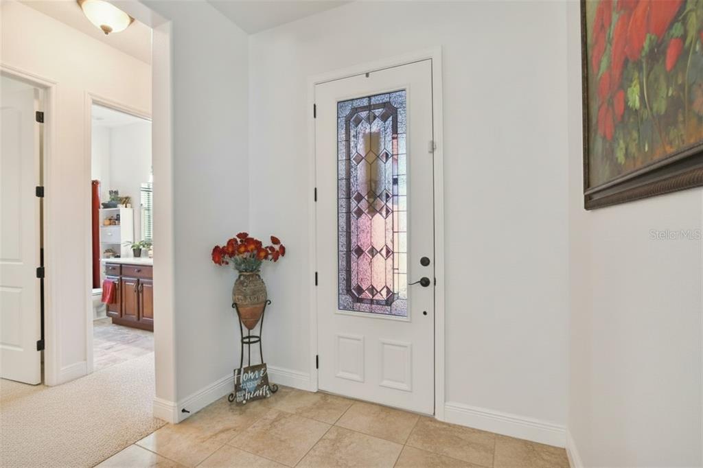 An entryway features a white front door with a decorative glass insert and tile flooring — 806 EBB TIDE LANE, KISSIMMEE, FL