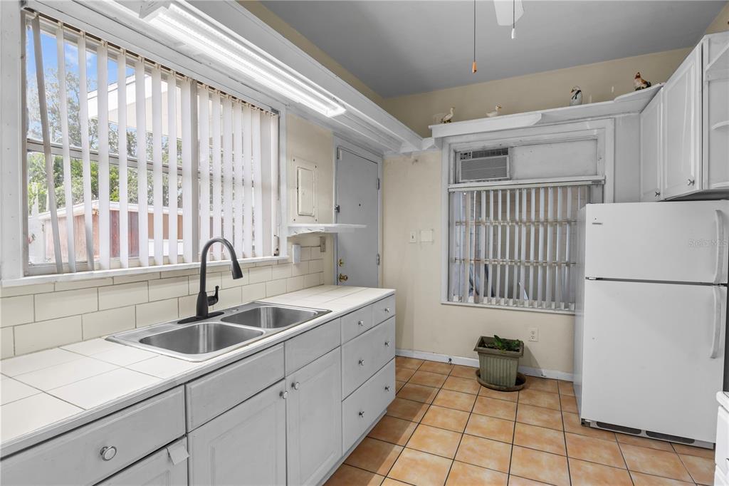 A kitchen features white cabinets, tiled countertops, a double sink, and a white refrigerator — 4517 KENILWORTH BOULEVARD, SEBRING, FL