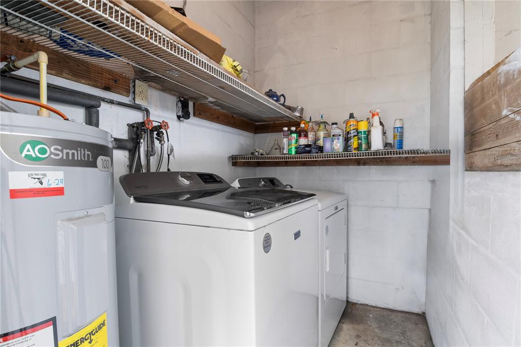 A laundry room features a water heater, white washing machine, dryer, and wire shelving units — 4517 KENILWORTH BOULEVARD, SEBRING, FL