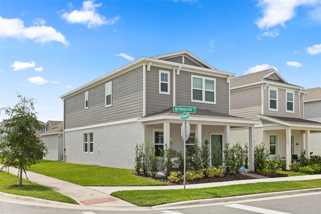 A two-story house with gray siding and a covered front porch sits on a corner lot — 750 HONEYROCK STREET, DEBARY, FL