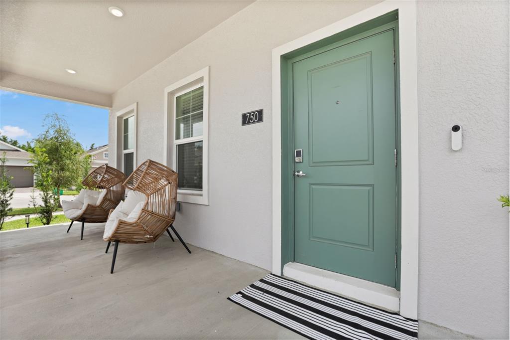 A covered porch features two wicker chairs, a green front door, and a striped mat — 750 HONEYROCK STREET, DEBARY, FL