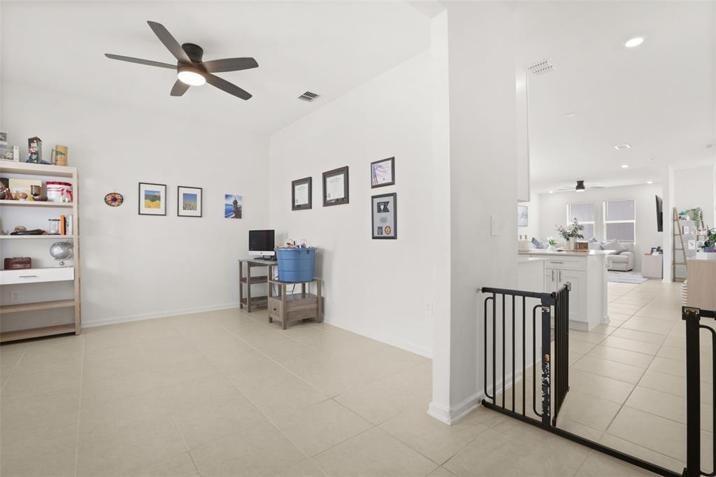 A bright room with tile flooring, a ceiling fan, and a view into the kitchen — 750 HONEYROCK STREET, DEBARY, FL