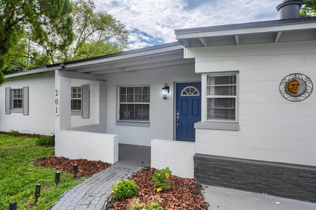 A white concrete block house features a blue front door and a covered porch — 201 HAYS DRIVE, SANFORD, FL