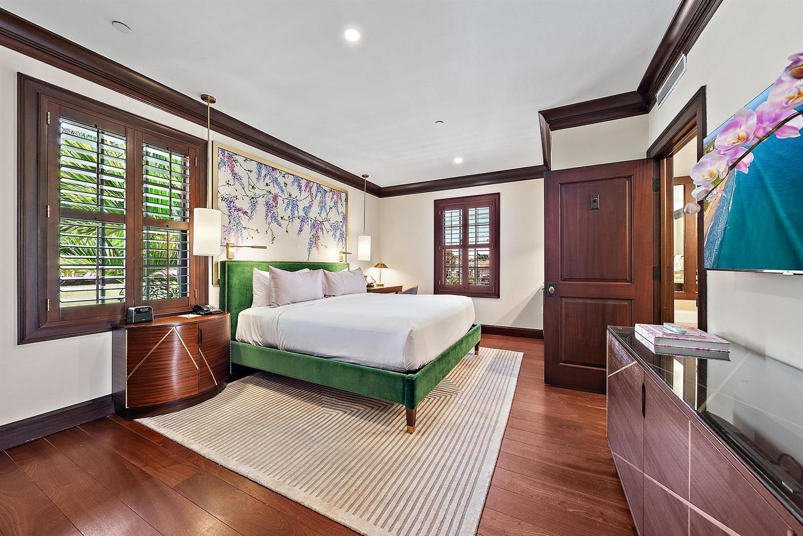 A bedroom features a green velvet bed, floral wall art, dark wood trim, and shutters — 301 Australian Avenue # 305, Palm Beach FL 33480, PALM BEACH, FL