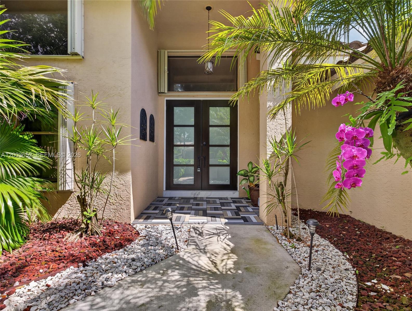 A front entryway features double glass doors, a patterned tiled porch, and surrounding tropical landscaping — 1025 Creekford Dr, Weston FL 33326, WESTON, FL