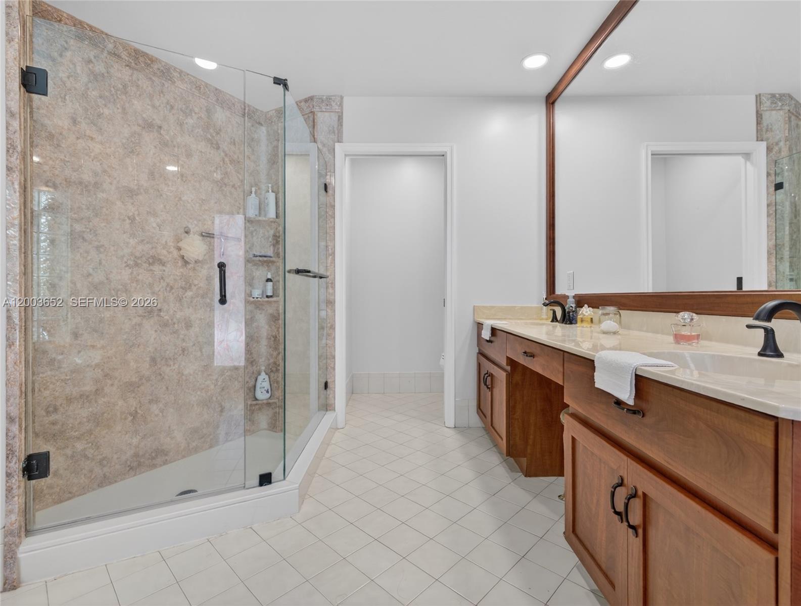 A bathroom features a glass-enclosed shower with stone tile and a wooden double vanity — 1025 Creekford Dr, Weston FL 33326, WESTON, FL