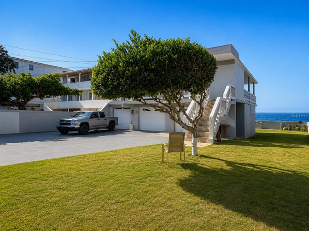 A two-story house with a garage, outdoor staircase, and a lawn overlooking the ocean — Mameyal EXT KENNEDY UNIT Mameyal wd, DORADO, PR