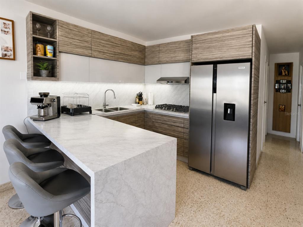 A modern kitchen features wood-grain cabinets, a marble-patterned island, and stainless steel appliances — Mameyal EXT KENNEDY UNIT Mameyal wd, DORADO, PR