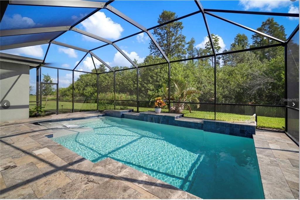 A screened-in patio features a rectangular swimming pool with a tiled water feature and pavers — 7004 MAINLAND AVENUE, APOLLO BEACH, FL