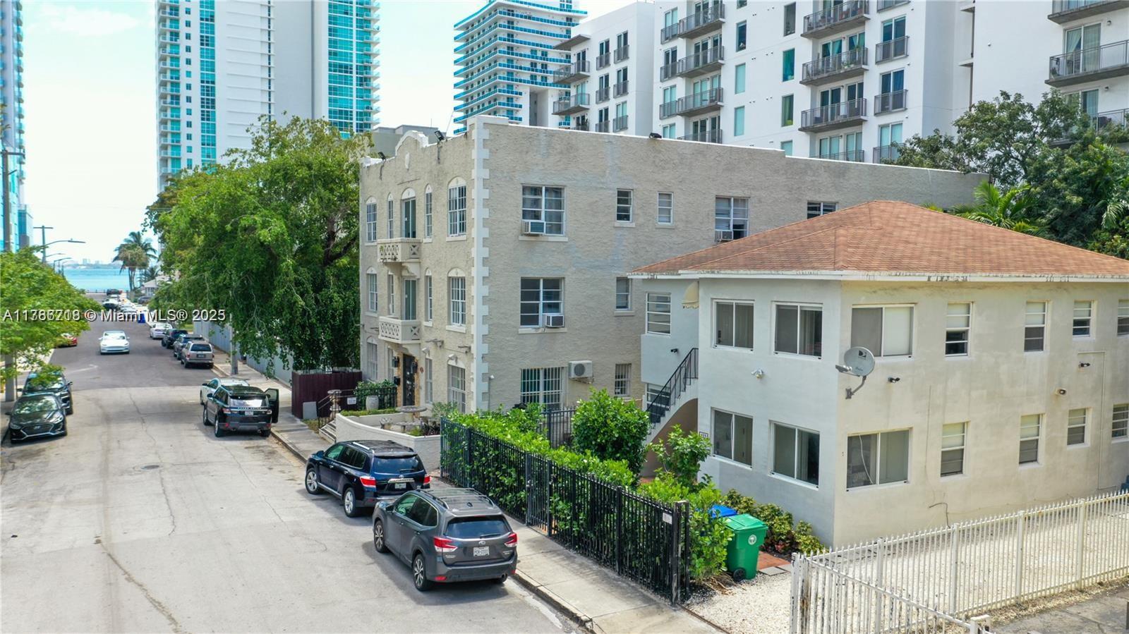An exterior view shows two multi-story apartment buildings along a street with parked cars — 426 NE 26th St, Miami FL 33137, MIAMI, FL