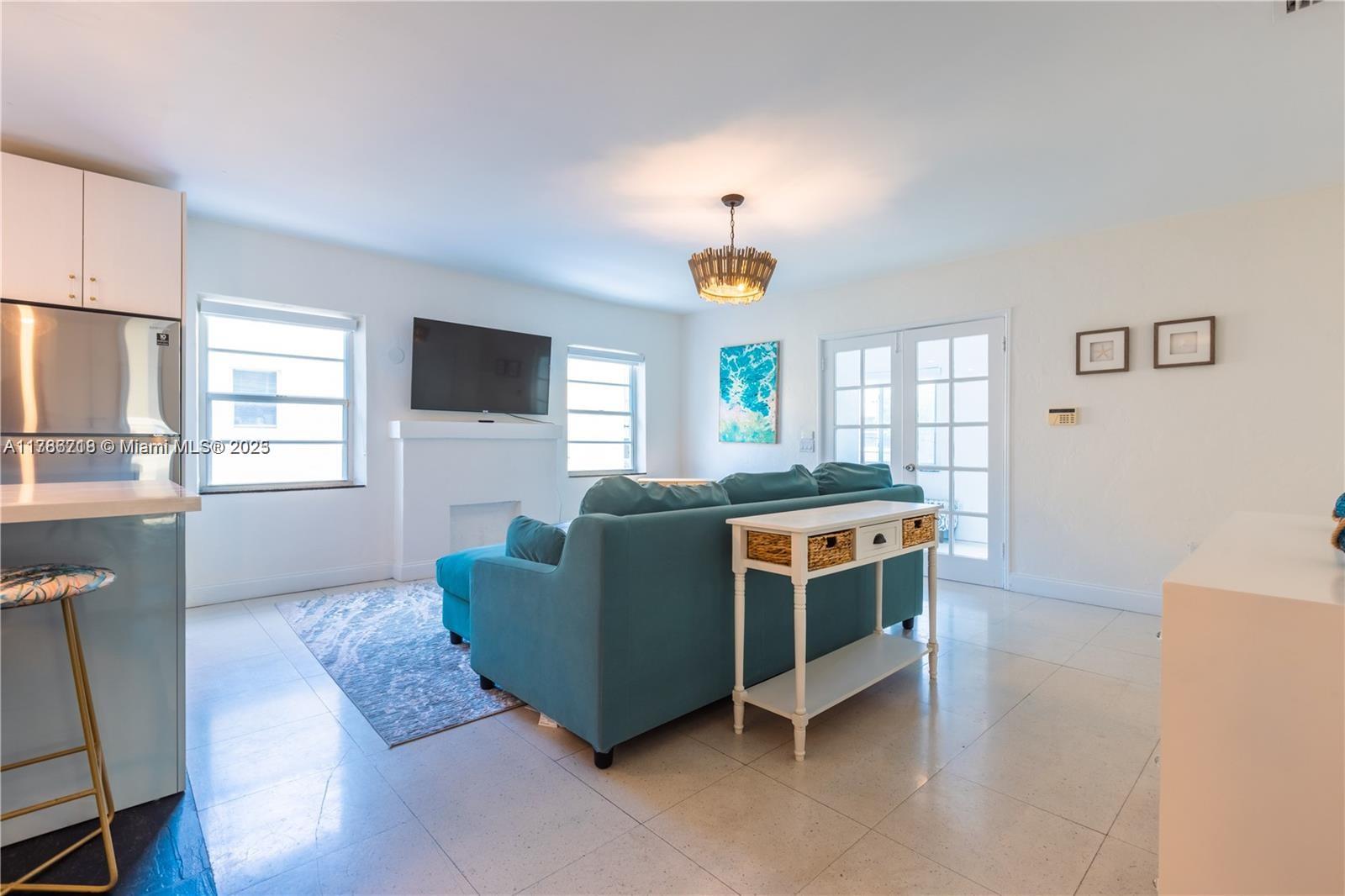 A living room features a teal sofa, a white console table, and a wall-mounted television — 426 NE 26th St, Miami FL 33137, MIAMI, FL