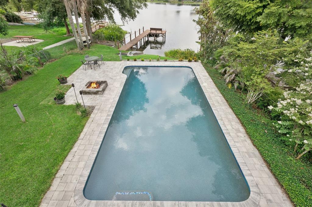 An aerial view of a rectangular swimming pool, stone patio, fire pit, and lake dock — 2939 DAWLEY AVENUE, ORLANDO, FL