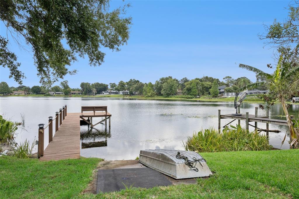A wooden dock extends into a lake from a grassy yard with an overturned boat — 2939 DAWLEY AVENUE, ORLANDO, FL