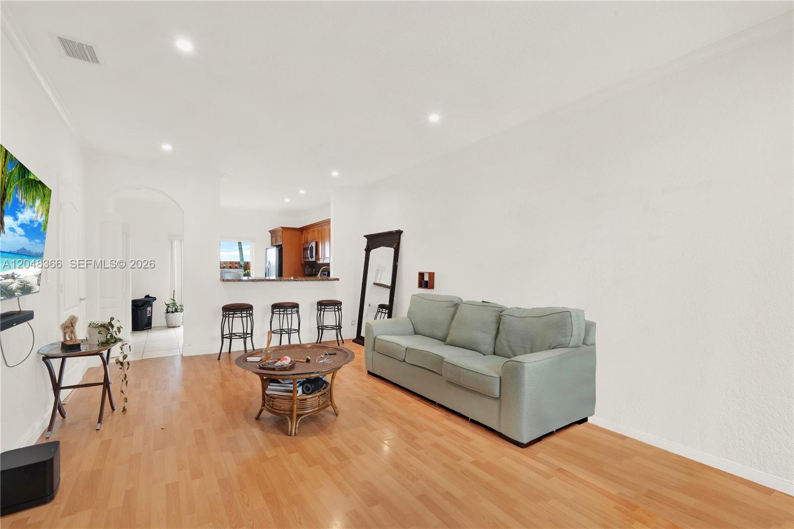 A living room features light wood flooring, a light green sofa, and an open kitchen — 17066 SW 138th Ct # 17066, Miami FL 33177, MIAMI, FL