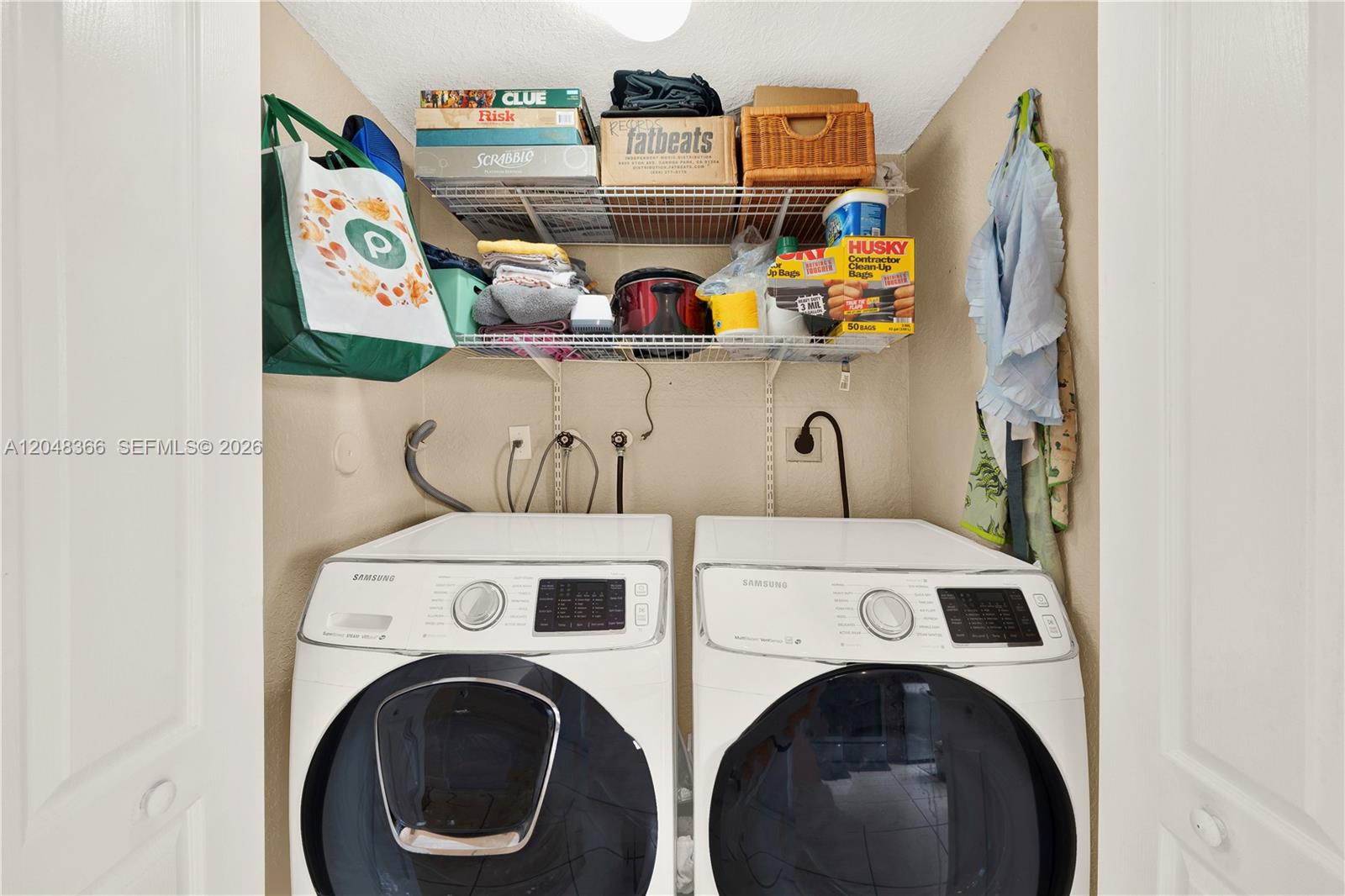 A laundry closet contains two white Samsung front-load machines beneath wire shelving with various items — 17066 SW 138th Ct # 17066, Miami FL 33177, MIAMI, FL