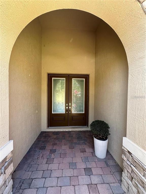 A covered entryway features a double door with glass panels and a paved floor — 8244 PRESTBURY DRIVE, ORLANDO, FL
