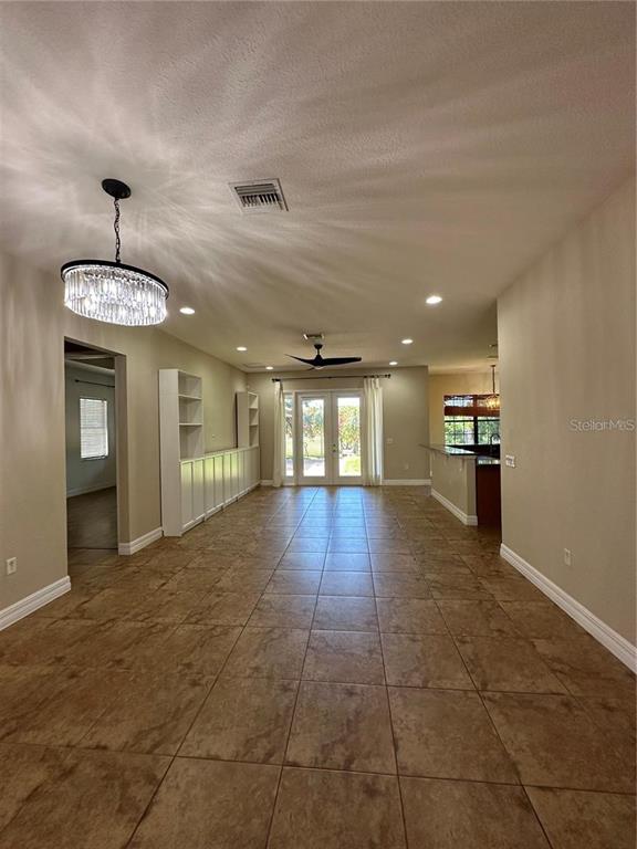 A spacious room with tile flooring, a crystal chandelier, and built-in shelving — 8244 PRESTBURY DRIVE, ORLANDO, FL