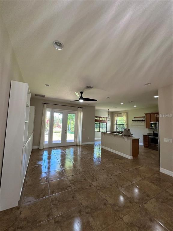 A living room with tile floors, a ceiling fan, and an open kitchen with cabinets — 8244 PRESTBURY DRIVE, ORLANDO, FL