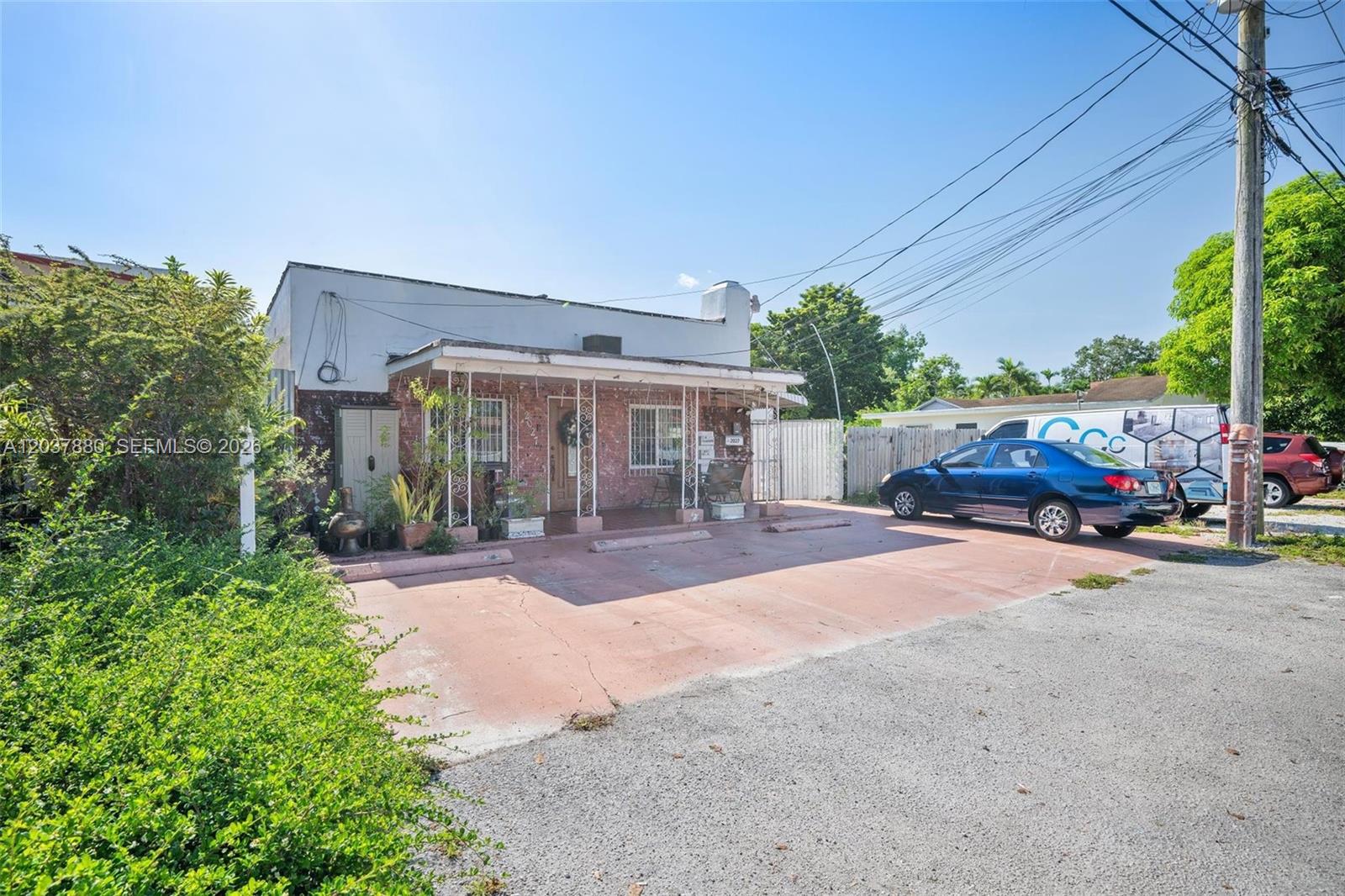 A single-story building with a brick facade and a covered front porch sits beside a driveway — 2027 SW 58th Ave, Miami FL 33155, MIAMI, FL
