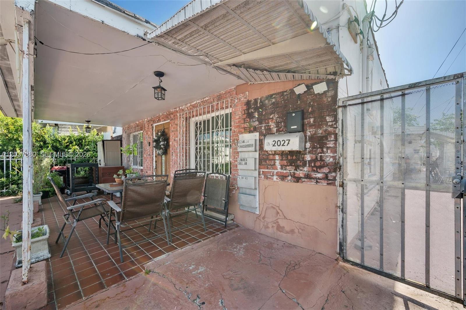 A covered patio features a tiled floor, outdoor furniture, and a brick wall with mailboxes — 2027 SW 58th Ave, Miami FL 33155, MIAMI, FL