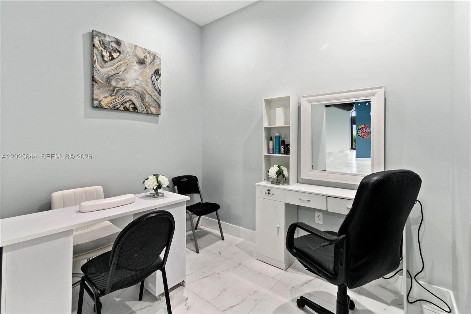 A salon interior features white marble floors, a sliding glass door, and grey velvet chairs — MIRAMAR, FL