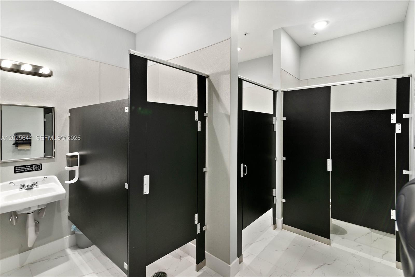A room features a wooden bookshelf, three black chairs with attached desks, and white flooring — MIRAMAR, FL