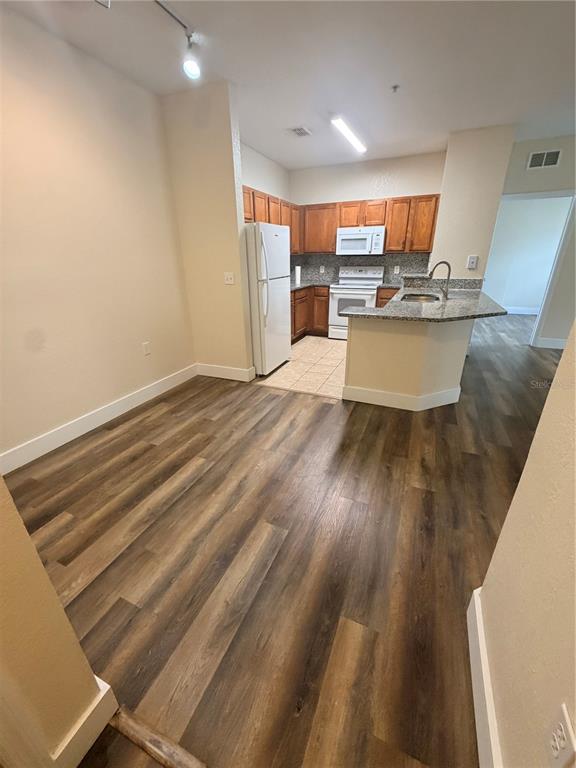 A kitchen with wood cabinets, stainless steel appliances, and a granite breakfast bar — 8137 CLAIRE ANN DRIVE UNIT 207, ORLANDO, FL