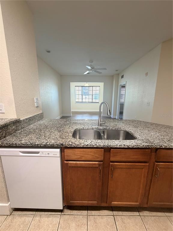 A kitchen island with a stainless steel sink and dishwasher faces an open living area — 8137 CLAIRE ANN DRIVE UNIT 207, ORLANDO, FL