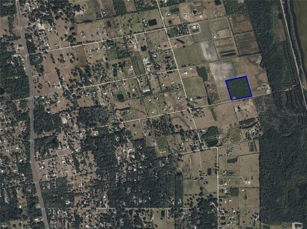 An aerial view shows a rectangular plot of land highlighted in blue amidst rural fields — 0 ORLANDO AVENUE, MIMS, FL