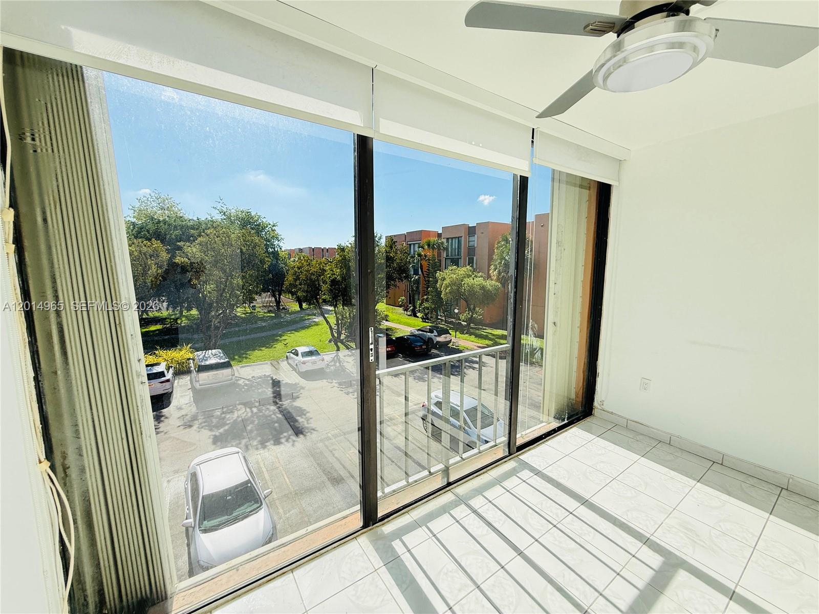A sunroom with white tile floors, a ceiling fan, and large windows overlooking a parking lot — 9440 W Flagler St # 305, Miami FL 33174, MIAMI, FL