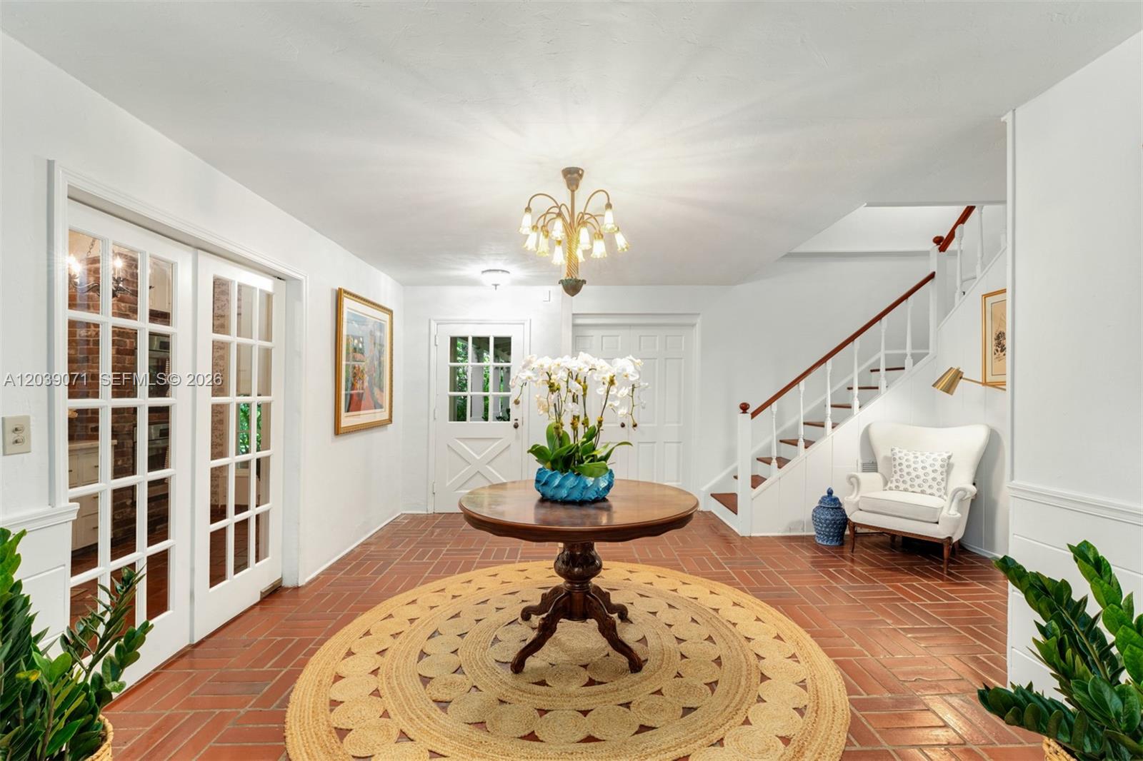 A bright foyer features a round wooden table, terracotta tile floors, and a staircase — 5950 SW 128th St, Pinecrest FL 33156, PINECREST, FL