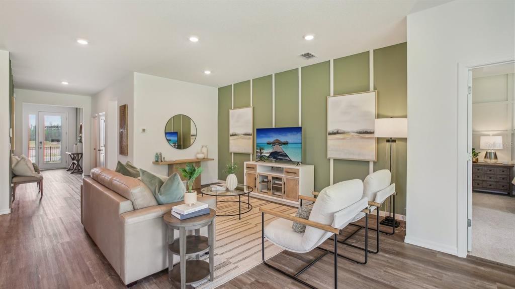 A living room features a green accent wall with white trim, a sofa, and chairs — 32745 WEATHERED OAK DRIVE, WESLEY CHAPEL, FL