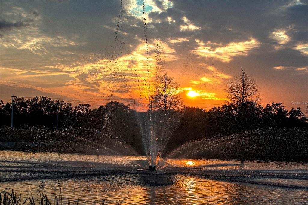 A water fountain sprays in the center of a pond during a golden sunset — 7009 166TH PLACE E, PARRISH, FL