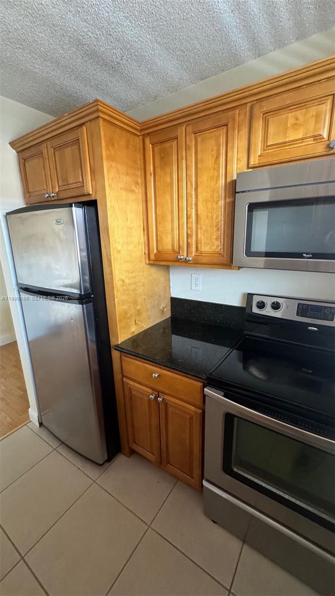 A kitchen features light wood cabinets, stainless steel appliances, and black countertops — 2441 SW 31st Ave # 303, Miami FL 33145, MIAMI, FL