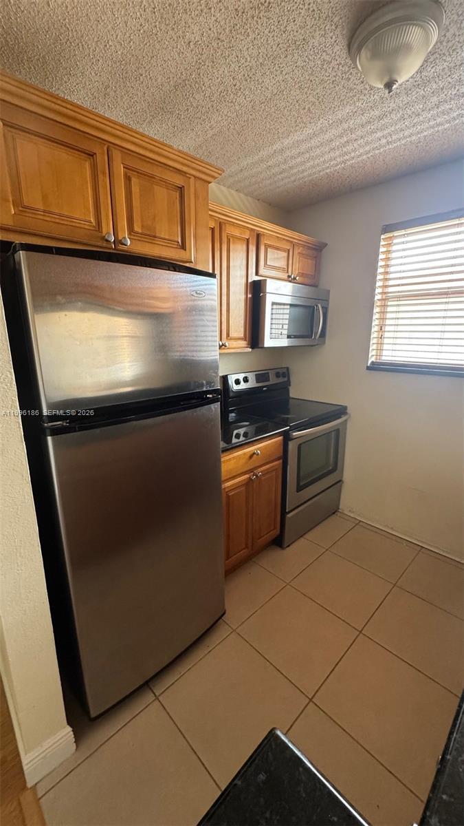 A kitchen features stainless steel appliances, wooden cabinets, and light-colored floor tiles — 2441 SW 31st Ave # 303, Miami FL 33145, MIAMI, FL