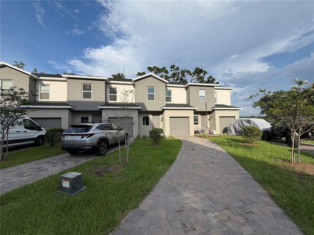 A multi-unit townhouse complex features gray stucco facades, paved driveways, and attached garages — 1209 SOUTHSTATION PLACE UNIT 308, ORLANDO, FL