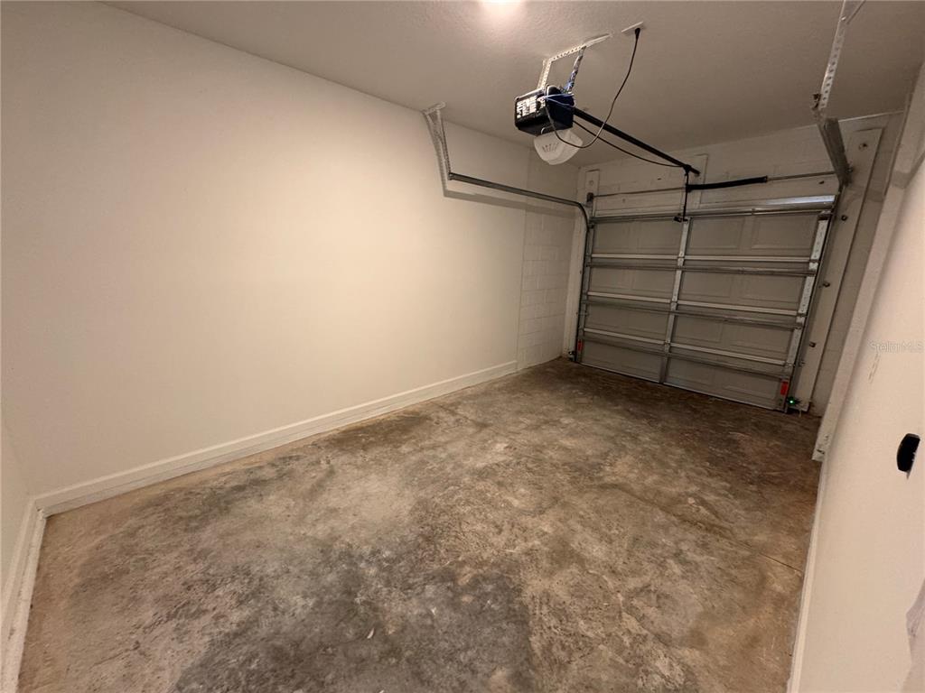 An empty garage features a concrete floor, white walls, and a metal sectional door — 1209 SOUTHSTATION PLACE UNIT 308, ORLANDO, FL