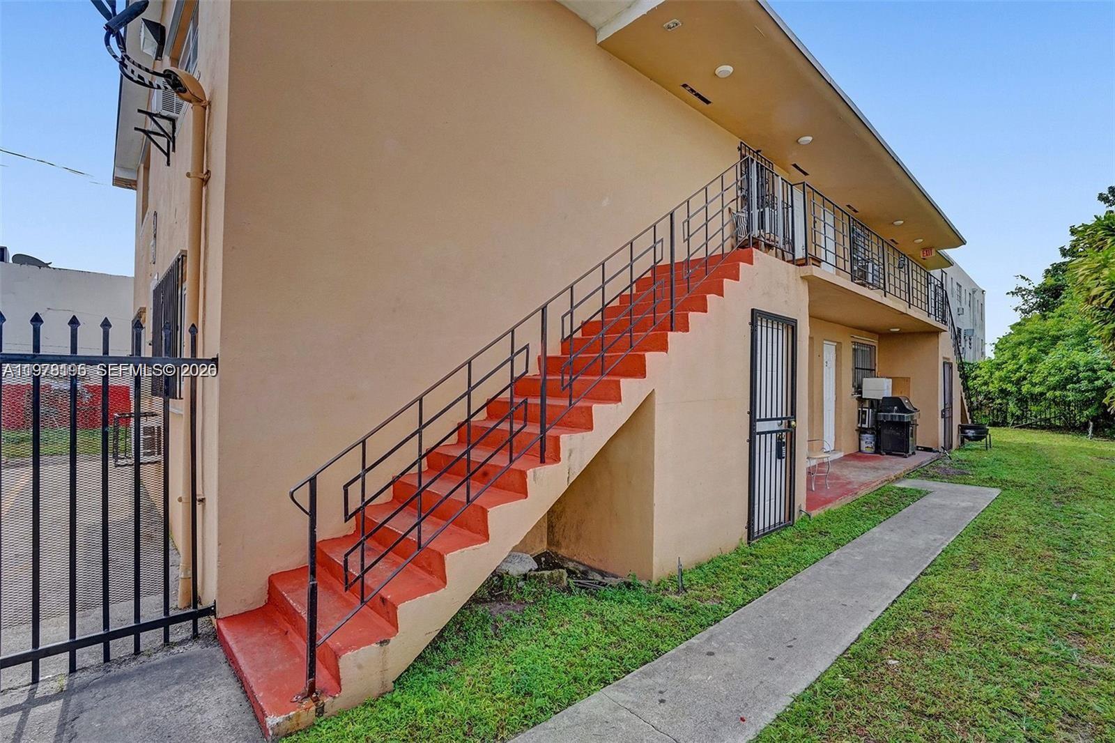 An exterior view shows an apartment building with an orange staircase leading to a balcony — 5842 NW 12th Ave, Miami FL 33127, MIAMI, FL