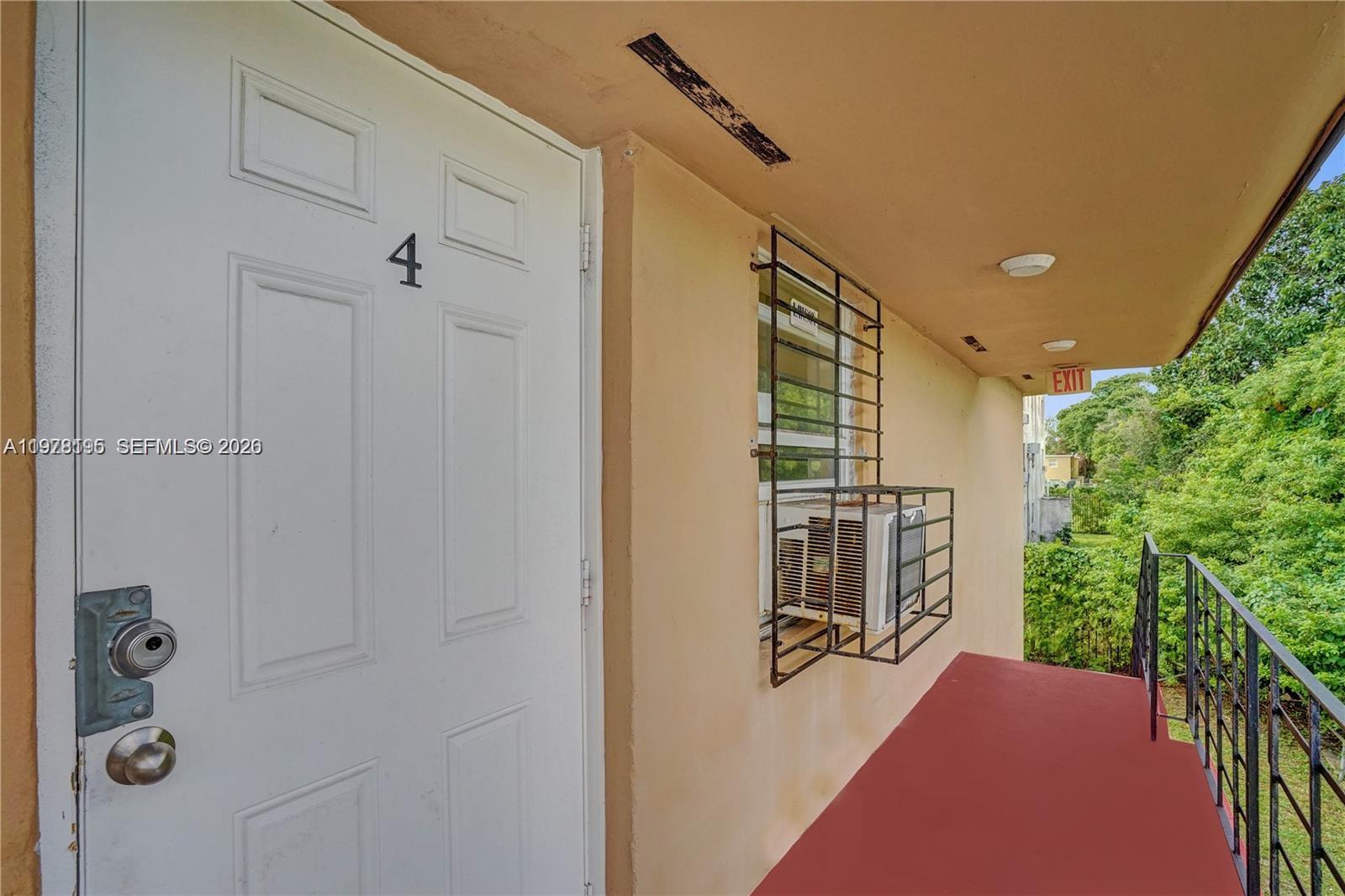A white door marked with the number four sits beside a window with a security cage — 5842 NW 12th Ave, Miami FL 33127, MIAMI, FL