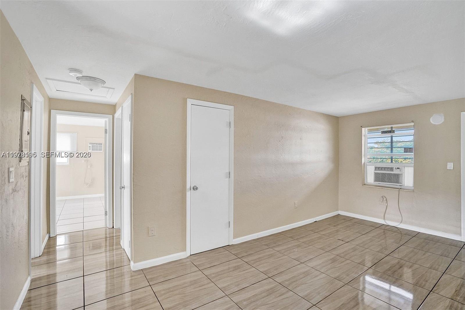 A room with tan walls, tiled floors, a window with an air conditioner, and two doors — 5842 NW 12th Ave, Miami FL 33127, MIAMI, FL