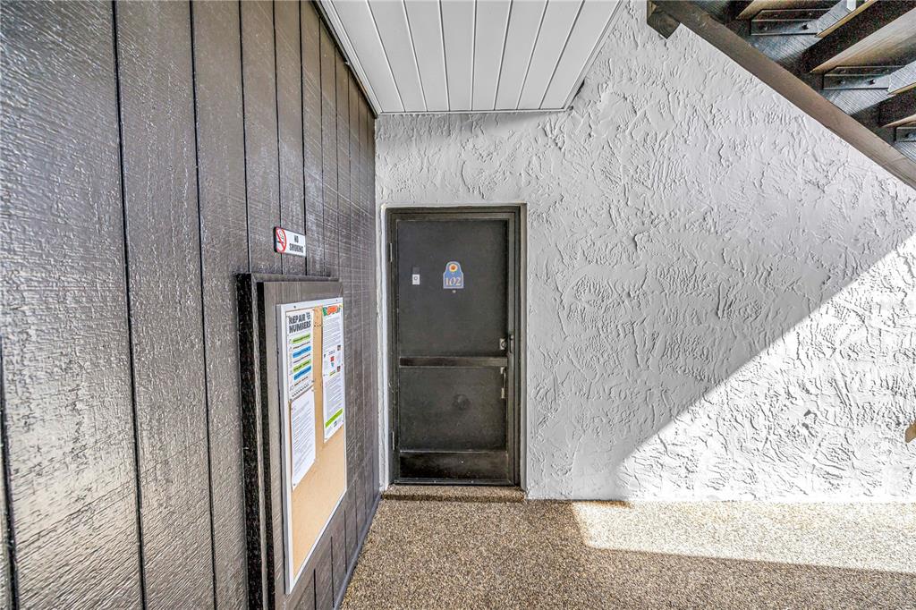 An exterior view of a building entrance featuring a dark door labeled 102 — 3269 BENEVA ROAD UNIT 102, SARASOTA, FL