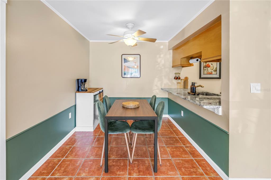 A dining area features a wooden table, four green chairs, tile flooring, and a kitchenette — 3269 BENEVA ROAD UNIT 102, SARASOTA, FL