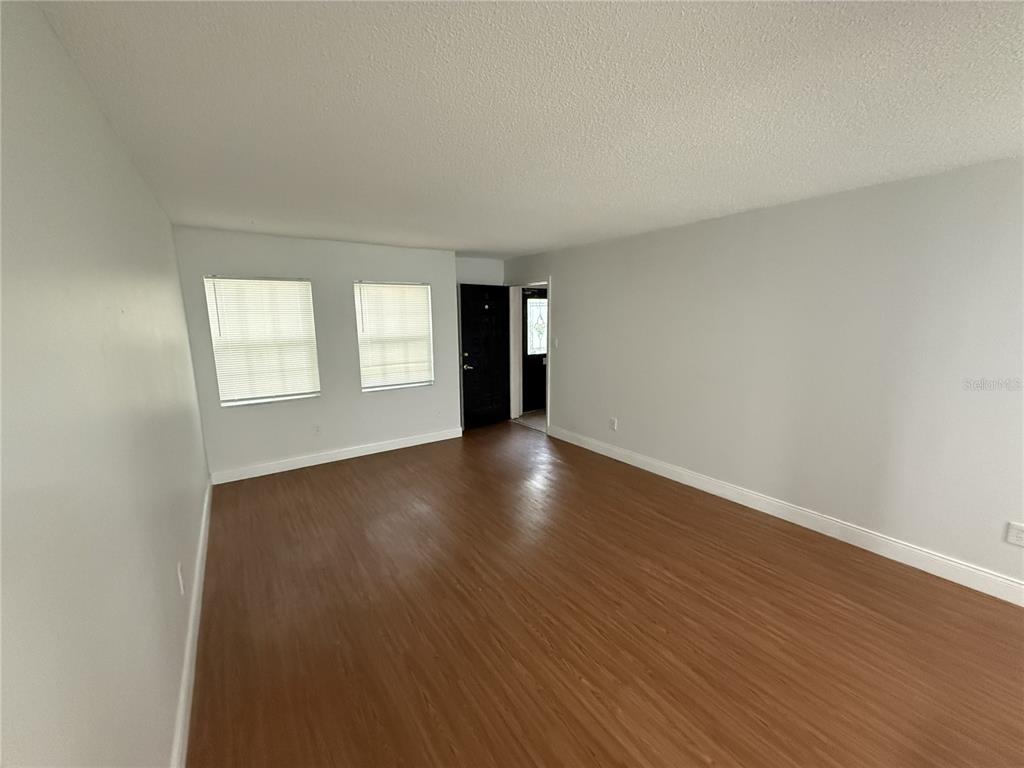 An empty living room features light gray walls, wood-look flooring, and two windows — 726 EDGEWATER DRIVE UNIT 2, ORLANDO, FL