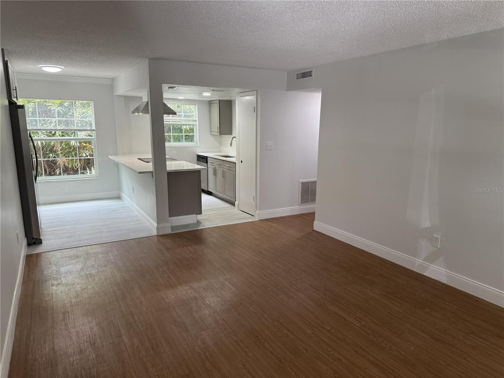 A living room with wood-look flooring leads to an open kitchen with gray cabinets — 726 EDGEWATER DRIVE UNIT 2, ORLANDO, FL