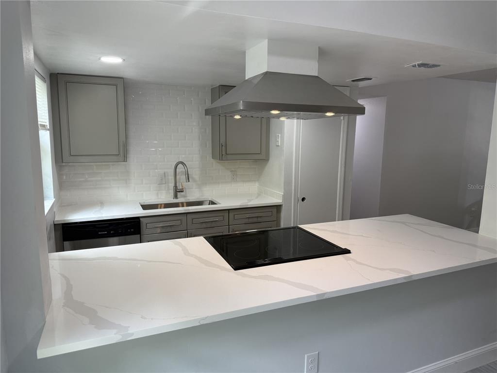 A kitchen features gray cabinets, white subway tile backsplash, quartz countertops, and a central island — 726 EDGEWATER DRIVE UNIT 2, ORLANDO, FL