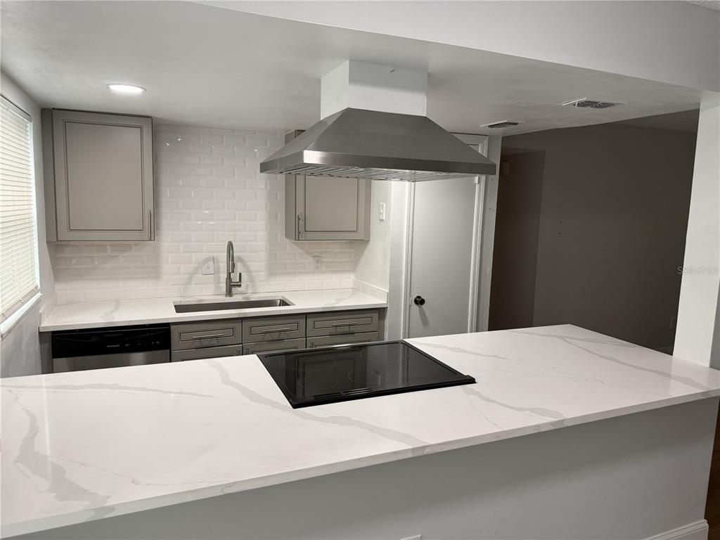 A modern kitchen features white marble-look countertops, grey cabinets, a subway tile backsplash, and an island — 726 EDGEWATER DRIVE UNIT 2, ORLANDO, FL