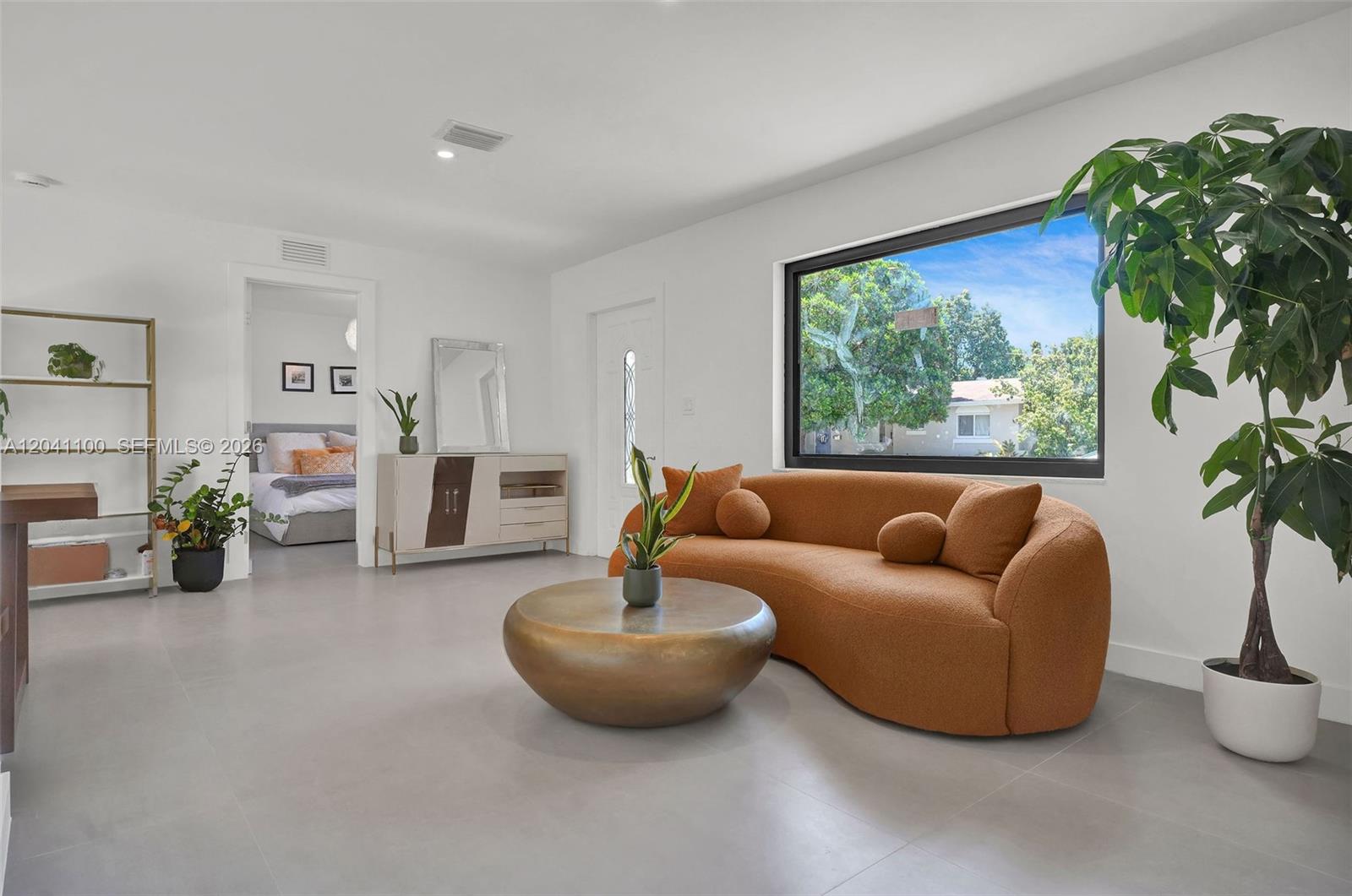 A living room features a curved orange sofa, a gold coffee table, and tile flooring — 211 Washington Dr, Coral Gables FL 33133, CORAL GABLES, FL