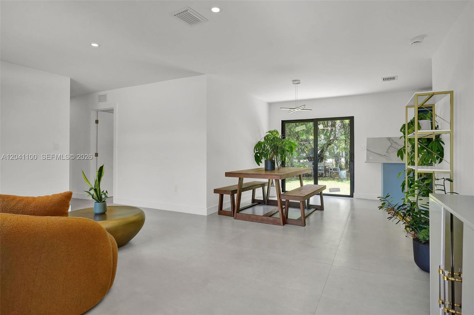 A bright dining and living area features white walls, tile flooring, and a wooden table — 211 Washington Dr, Coral Gables FL 33133, CORAL GABLES, FL
