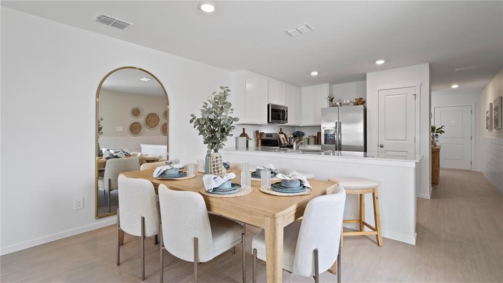 A dining area with a wooden table and chairs sits adjacent to a white kitchen — 286 CERAMIC COURT, GROVELAND, FL