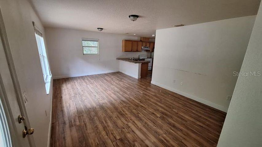 A living area with wood-look flooring opens to a kitchen featuring wood cabinets and countertops — 788 N CHARLES AVENUE, INVERNESS, FL
